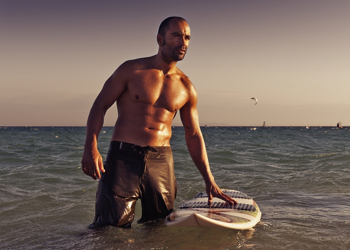 A Man With His Surfboard In The Water At Sunset; Tarifa Cadiz Andalusia Spain