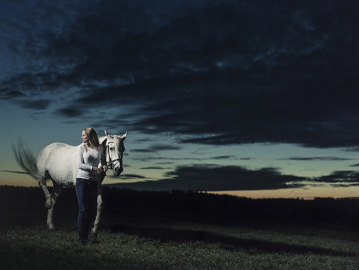 Girl standing next to her horse at dusk, Freising, Bavaria, Germany, Photo by Feder, Wilfried