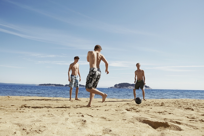 Men playing soccer on beach