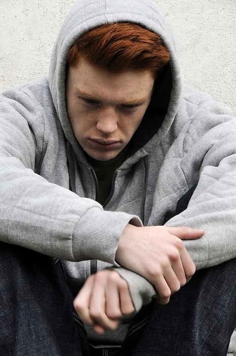 Depressed teenager Depressed teenager. 18 year old depressed teenage boy gazing at the ground.