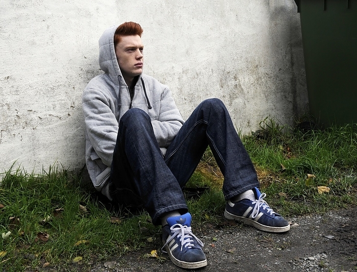 Depressed teenager Depressed teenager. 18 year old depressed teenage boy sitting on the ground against a wall.