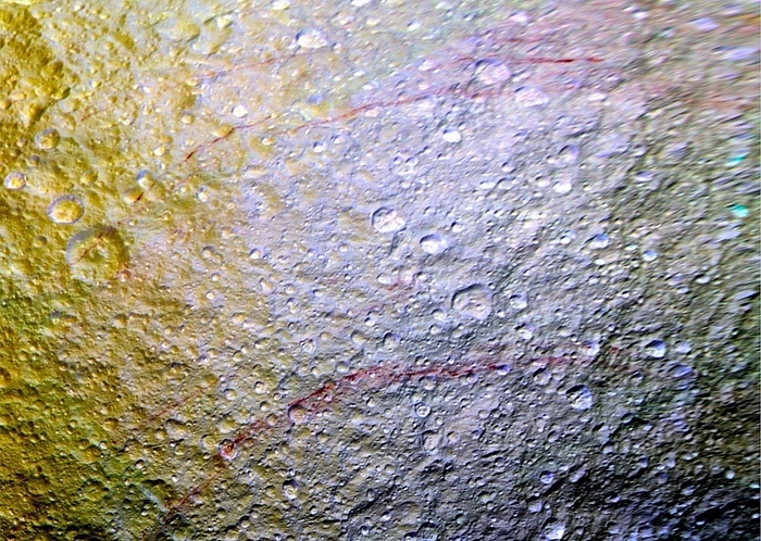Saturn s moon Tethys, Cassini image Saturn s moon Tethys. Enhanced colour mosaic satellite image showing unusual arc shaped reddish streaks cut across the surface of Saturn s moon Tethys. Tethys  1060 kilometres diameter  is composed almost entirely of pure water ice. The high reflectivity  albedo  of the icy surface makes Tethys the brightest moon orbiting Saturn and one of the brightest objects in the solar system. The red streaks are narrow lines on the surface, only a few kilometres wide but several hundred kilometres long. Their origin is currently unknown but possibilities include ideas that the reddish material is exposed ice with chemical impurities, or the result of outgassing from inside Tethys. The streaks could also be associated with features like fractures that are below the resolution of the available images. Composed from images obtained by the Cassini Orbiter, on 11th April 2015.