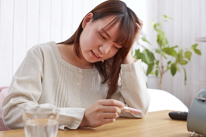 Japanese woman with her head in her hands when she sees a pregnancy test
