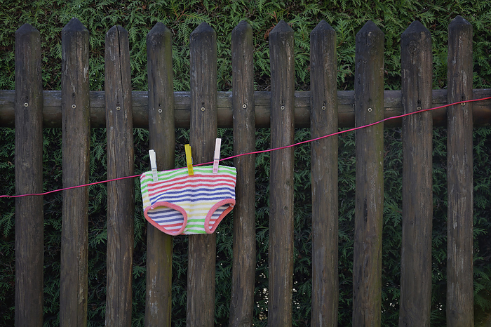 Colorful underpants drying on clothesline in front of wooden fence