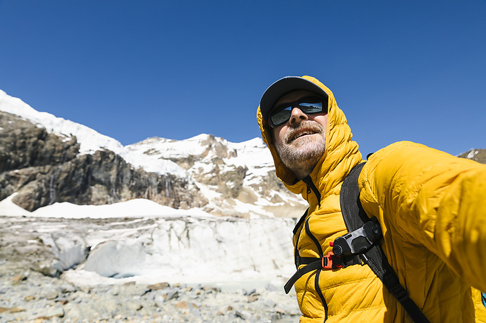 Smiling mature man standing against snowcapped mountain