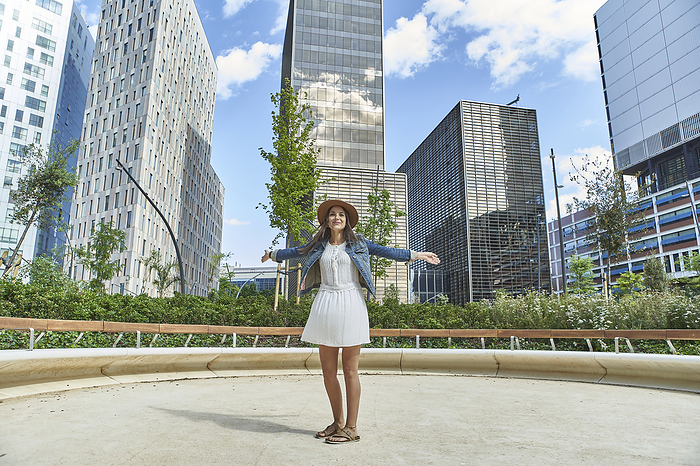 female Cheerful woman standing with arms outstretched in modern city