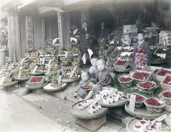 Store  Date of photograph unknown  Two men and several children in a fruit store. Commonly eaten fruits in Japan during the Meiji Period  1868 1912  were mikan, melon, kaki  persimmon , biwa  loquat , nashi  pear , plum, apricot, peach and apple.