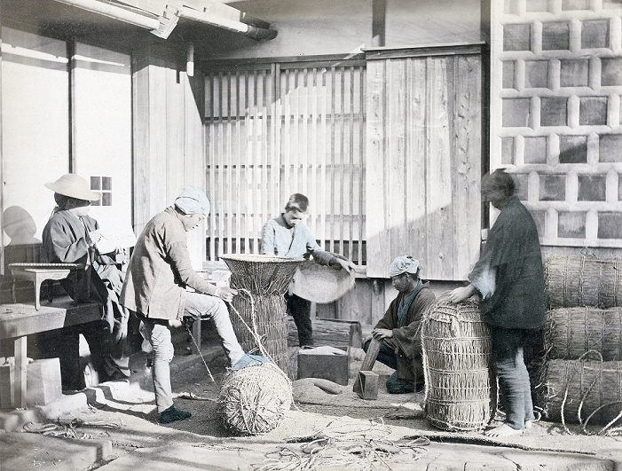 Bale of rice  Date of photograph unknown  Two men in the foreground are packing rice in straw bags, while the man on the left is taking records. A soroban  Japanese abacus  lies on the table next to him. In the back a boy is filling a still open bag with rice. A masu wooden measuring box lies on the ground. Masu existed in many sizes from 0.9 to 18 liters.