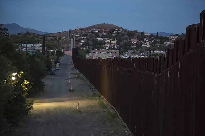 US Mexico border fence, Arizona, USA US Mexico border fence. View of the border fence separating Nogales, Arizona, USA  left  and Nogales, Sonora, Mexico  right  at dusk, with border patrol lights illuminating the US side.