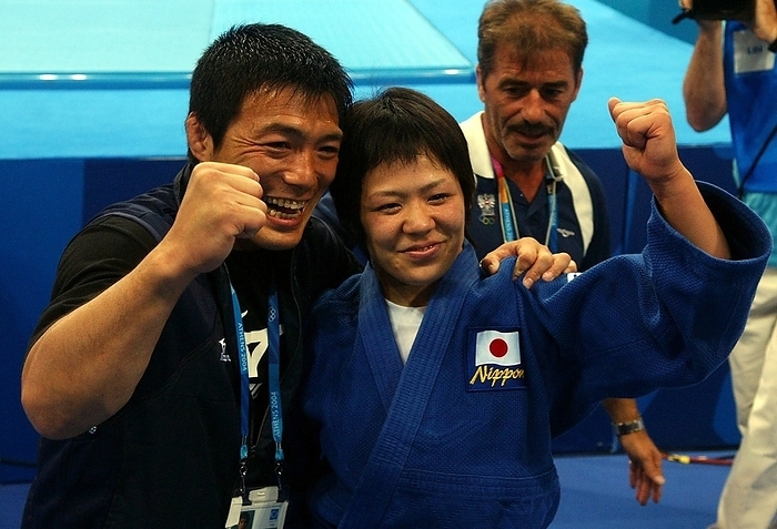 2004 Athens Olympic Games Judo Ayumi Tanimoto  right , who won the gold medal in the women s 63 kg weight class final, clasps her shoulders with coach Toshihiko Koga and strikes a gut wrenching pose in the Ano Liosia Olympic Hall  August 17, 2004   Location  Athens, Greece