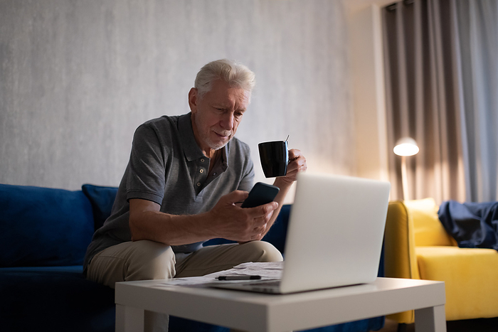 Aged man with cup using smartphone Aged man with cup using smartphone