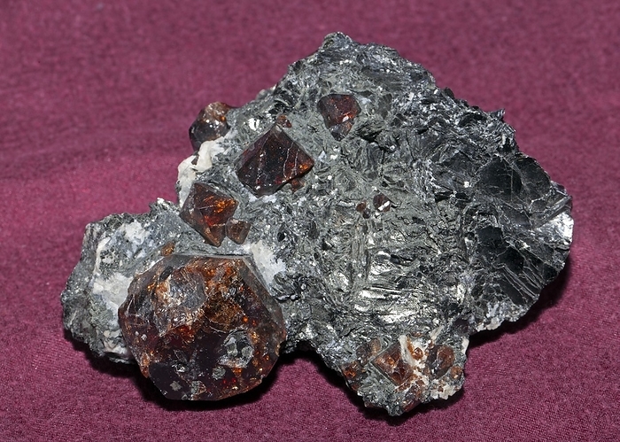 Almandine Almandine is a species of the garnet group, a silicate of the metals iron and aluminium  Fe3Al2Si3O12 . Its crystal system is isometric, the crystal habit often being well developed rhombic dodecahedral shapes, coloured a characteristic brownish red. It is found in schists and other metamorphic rocks, most often as individual crystals but also as crystal groups. The crystals here seen are embedded in a micaceous host rock from the Zillertal in Austria. Actual width of sample is 120 mm., by DIRK WIERSMA SCIENCE PHOTO LIBRARY