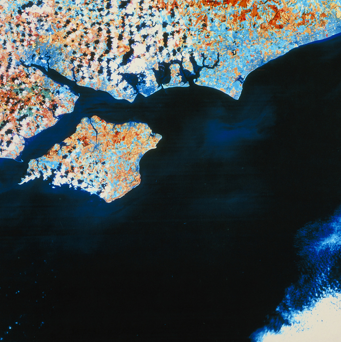 Isle of Wight   Hampshire coast   August Isle of Wight seen from space. False colour image of the Hampshire coast and the Isle of Wight, made by the Landsat 5 satellite in August 1986. The colours represent different surface cover. The red areas are natural pasture in late summer growth, the pale blue areas are healthy crops approaching harvest and tended grass  parks, etc. . Mid  blue indicates urban areas. Two major ports are seen  Southampton  top left at end of estuary  and Portsmouth  just left of centre on coast . Between the Isle of Wight and the mainland is The Solent, most of the image being the English Channel. Compare with spring view E076 055.
