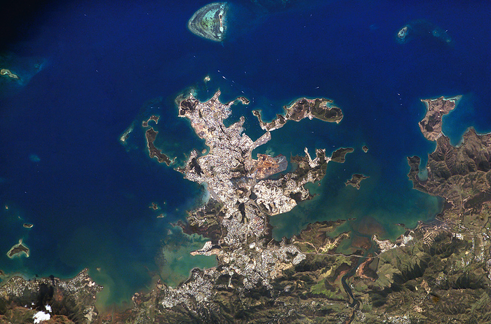 Noumea, New Caledonia Noumea, New Caledonia, seen from the International Space Station  ISS . The city sprawls over this peninsula that juts into a lagoon. The island is in the southern tropics of the Pacific Ocean, and so coral reefs  light blue, top centre  can form. Mountains  lower right  rise behind the city. They cover most of the island, and they are among the world s major sources of nickel and chromium. New Caledonia is an overseas territory of France. The 1989 population of Noumea, its capital city, was 65,110. This area is about 50 kilometres wide. The ISS orbits the Earth at an altitude of around 380 kilometres. Photographed on 13 September 2003.
