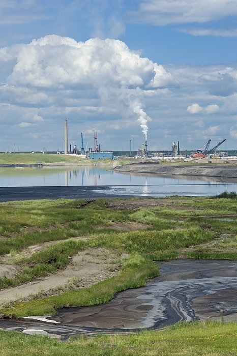 Oil industry pollution Oil industry pollution. Tailings settling pond with residual crude oil and bitumen floating on the surface and accumulating on the shoreline. In the background is the Syncrude oil processing plant. Photographed in the Athabasca Oils Sands, Alberta, Canada.