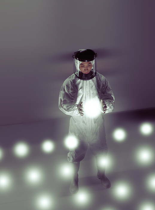 Biotechnologist working with samples MODEL RELEASED. Biotechnologist in a full protective suit working with glowing samples in a laboratory.