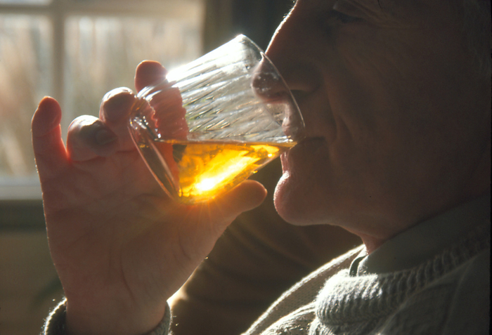 Profile of a man drinking alcohol Alcohol consumption. Profile of a man drinking a glass of alcohol. Alcohol is an addictive substance which acts as a depressant on the nervous system, and so reduces anxiety, tension and inhibitions. Dependency on alcohol  alcoholism  is an illness which leads to withdrawal symptoms when drinking is suddenly stopped. Long term and excessive alcohol consumption may cause irreversible damage to the heart, liver, brain and nervous system.