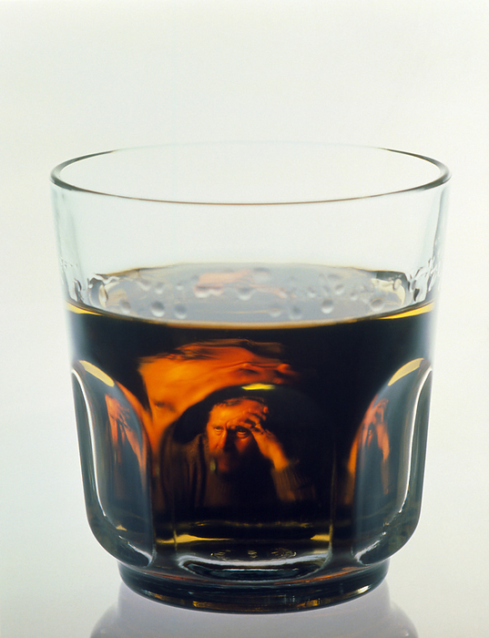 Glass of alcohol with alcoholic man Alcohol addiction. Glass of alcohol, with an abstract image of a man reflected in the liquid. In his expression, the man appears to be struggling with his addiction. Alcohol is an addictive substance which acts as a depressant on the nervous system, and so reduces anxiety, tension and inhibitions. Dependency on alcohol  alcoholism  is an illness which leads to withdrawal symptoms when drinking is suddenly stopped. Long term and excessive alcohol consumption may cause irreversible damage to the heart, liver, brain and nervous system.