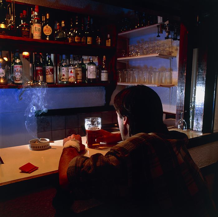Alcoholism Alcoholism. Alcoholic man drinking by himself at a bar. Alcohol decreases the activity of the central nervous system, reducing anxiety and inhibitions. In the long term, alcohol is addictive and can cause liver problems, heart disease, high blood pressure and brain damage.