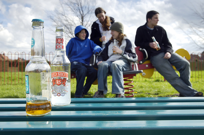 Underage drinking MODEL RELEASED. Underage drinking. Group of teenagers drinking in a park.