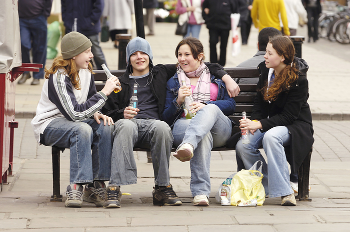 Underage drinking MODEL RELEASED. Underage drinking. Group of teenagers drinking on a bench.