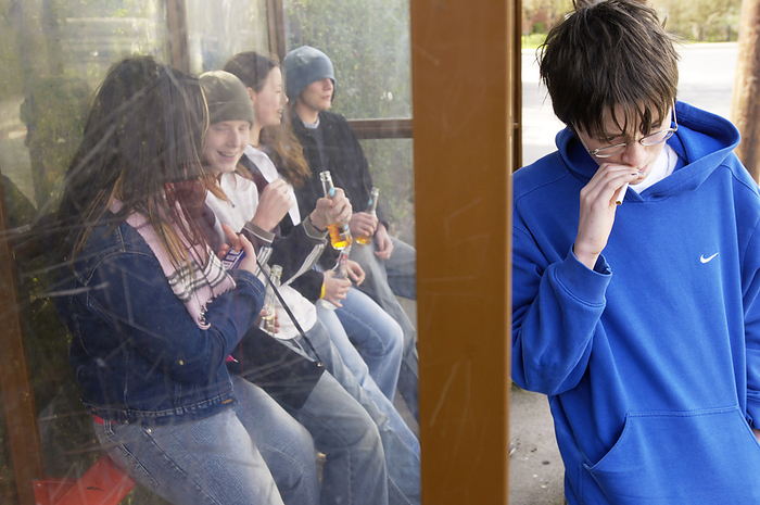 Underage drinking MODEL RELEASED. Underage drinking. Group of teenagers drinking and smoking in a bus shelter.