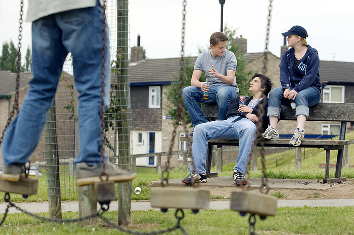Teenagers drinking and socialising MODEL RELEASED. Teenagers socialising in a park.