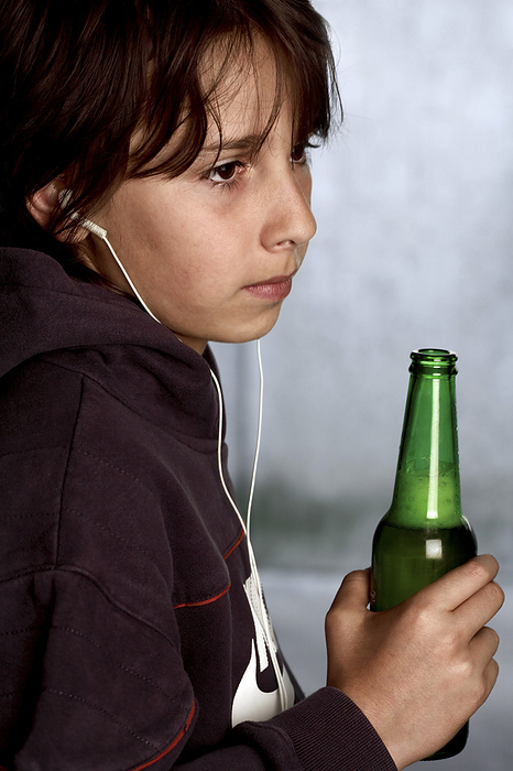 Underage drinking MODEL RELEASED. Underage drinking. Nine year old boy wearing headphones and holding a beer bottle.