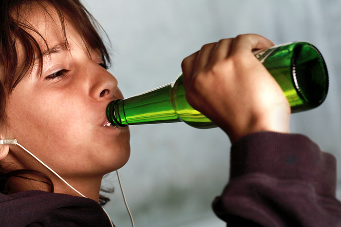 Underage drinking MODEL RELEASED. Underage drinking. Nine year old boy wearing headphones and drinking a bottle of beer.