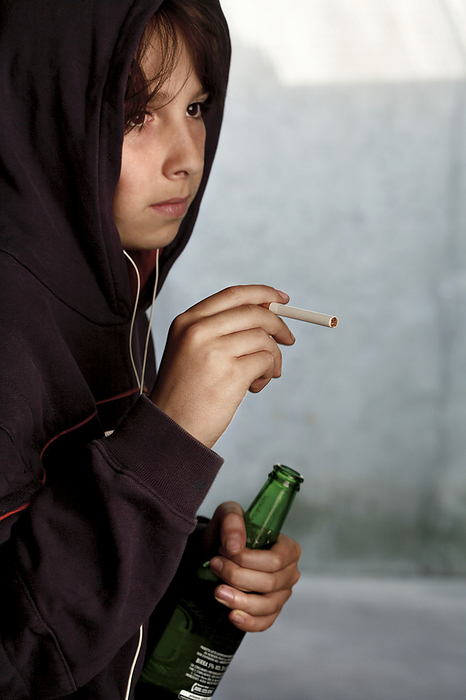 Underage smoking and drinking MODEL RELEASED. Underage smoking and drinking. Nine year old boy holding a cigarette and a bottle of beer.