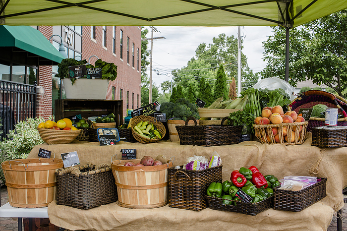 A small farm stand piled with baskets of fresh fruits and vegetables