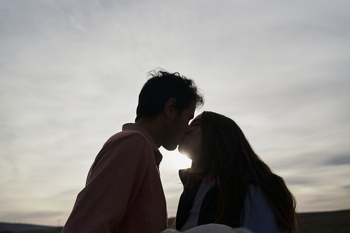 couple Beautiful young couple kissing at sunset in a park. Romantic concept