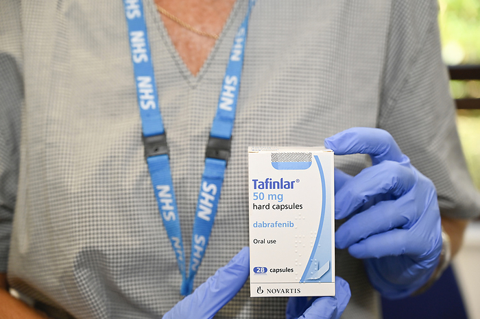 Dabrafenib cancer drug packaging Healthcare worker holding Dabrafenib cancer drug packaging. This medication, marketed as Tafinlar, is a cancer growth blocker drug used to treat melanoma skin cancer and advanced non small cell lung cancer. Dabrafenib is used in patients that have a mutation in the BRAF gene. Dabrafenib blocks the abnormal protein produced that signals for cancer cells to multiply., by DR P. MARAZZI SCIENCE PHOTO LIBRARY
