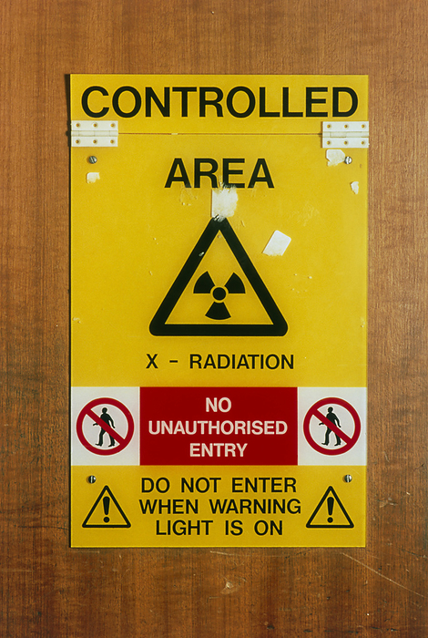 View of an X ray warning sign in a hospital X ray warning sign. View of an X ray warning sign in a hospital. The sign warns the reader that they are about to pass into a controlled area where there is danger of exposure to X rays. At centre, is the internationally recognised radiation warning logo. Prolonged or repeated exposure to X rays can cause sterility, inflammation and ulceration of the skin and hair loss. It is therefore important to implement safety measures to prevent unnecessary exposure. X rays are used in diagnosis and therapeutically in the treatment of leukaemia and other diseases.