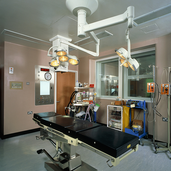 View of a modern operating theatre A modern operating theatre, a room designed to reduce the risk of infection in open surgical wounds. The room is equipped with shadowless lamps and a X ray screen  centre left below the watch   the anaesthetic trolley is seen at centre in the background. A ventilation system provides a constant supply of clean and filtered air  the walls and the floors are easily washable and there are adjoining rooms with foot  and elbow operated taps where surgeons and assistants scrub their hands and forearms before putting on their gowns, gloves and masks.