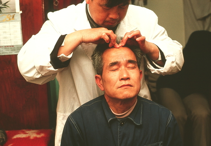 Acupressure Acupressure. Man receiving acupressure treatment to his head. Pressure is applied to specific areas of the body in order to relieve the symptoms of a variety of disorders. Practioners of traditional Chinese medicine believe that this treatment unblocks the channels through which the life force, or chi, should flow. Photographed on a boat on the Yangtze River, China.
