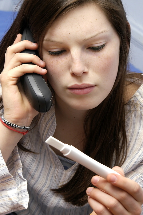 Home pregnancy testing MODEL RELEASED. Home pregnancy testing. Concerned young woman looking at the result of a home pregnancy test and making a phone call. The testers work by detecting the prescence of human chorionic gonadotropin  hCG  in the urine, a hormone secreted by the placenta of a pregnant woman.
