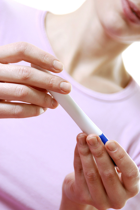 Home pregnancy test MODEL RELEASED. Home pregnancy test. Woman looking at the result of a home pregnancy test. This device works by detecting the presence of human chorionic gonadotropin  hCG  in urine, a hormone secreted by the placenta of a pregnant woman.