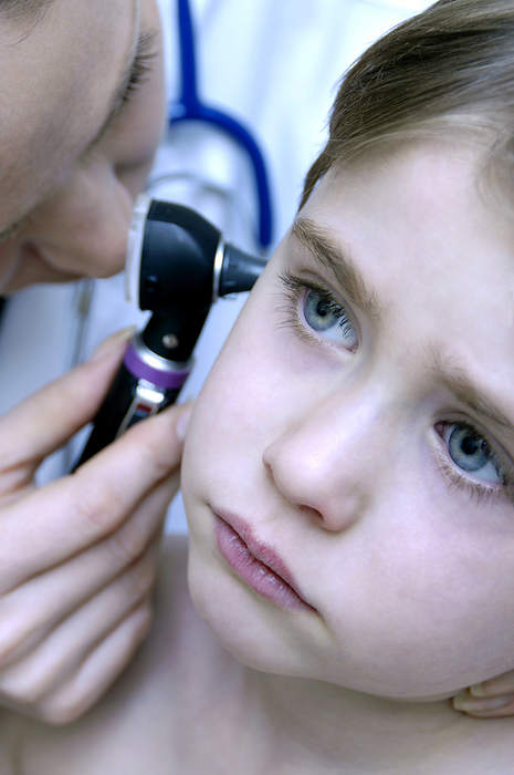 Ear examination MODEL RELEASED. Ear examination. Paediatrician using an otoscope to examine a young boy s sore ear.