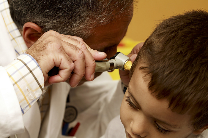Paediatric examination Paediatric examination. Doctor using an otoscope as he examines a young boy s ear. This device shines a light down the ear canal and magnifies the view. This allows the doctor to diagnose disorders such as an outer ear infection, or problems with the ear drum.