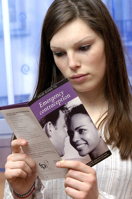 Emergency contraception information MODEL RELEASED. Emergency contraception information. Young woman reading a leaflet on emergency contraception. Emergency contraception comes in pill form and contains a type of progestin called levonorgestrel. It is thought to work by preventing or postponing ovulation, or by preventing the fertilised egg from implanting in the uterus.