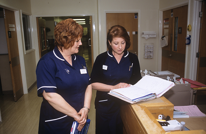 District Nurse and Senior Sister MODEL RELEASED. District nurse and Senior Sister discussing a patient s possible discharge from hospital. Photographed in Bognor Regis, West Sussex in England, UK.
