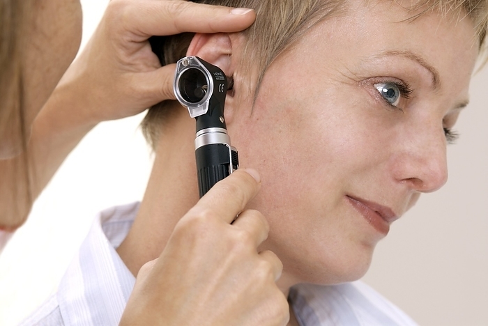 Ear examination Ear examination. ENT  ear nose and throat  consultant using an otoscope to examine a woman s ear.