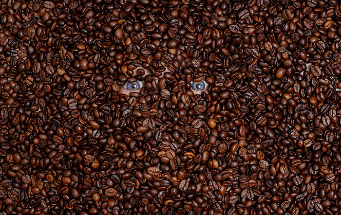 Human eyes buried in roasted coffee beans