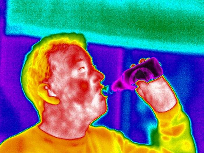 Drinking beer, thermogram MODEL RELEASED. Drinking beer. Thermogram of a man drinking a bottle of beer. The colours show variation in temperature. The scale runs from white  warmest  through red, yellow, green and blue to purple  coldest . The bottle of beer has been refrigerated. Thermography records the temperature of surfaces by detecting long  wavelength infrared radiation.