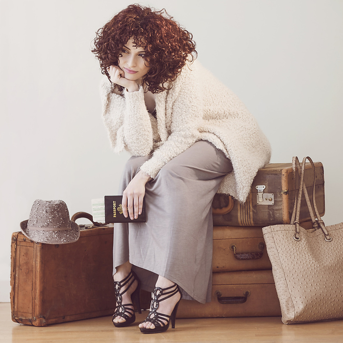 female Beautiful brunette woman sitting on suitcases