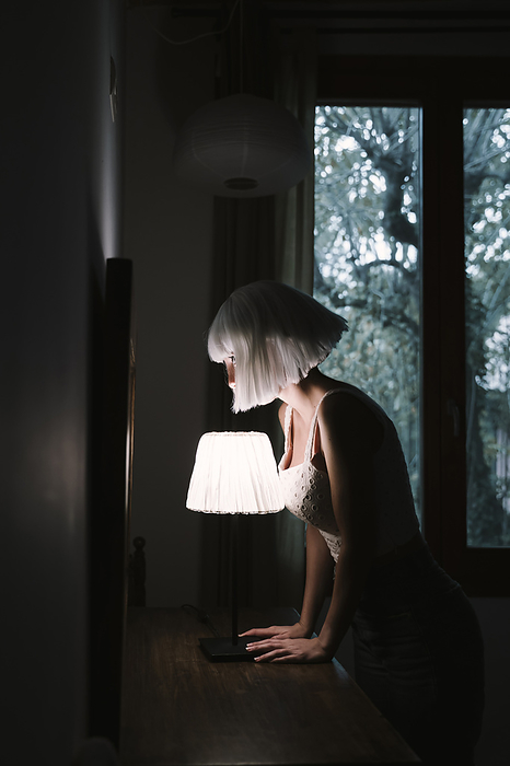 female Young woman standing by illuminated lamp at home, Photo by VITTA GALLERY