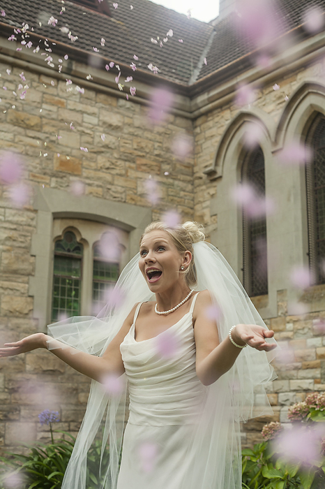 Carla.jpeg Surprised young bride standing amidst petal confetti at church, Photo by LOUIS CHRISTIAN