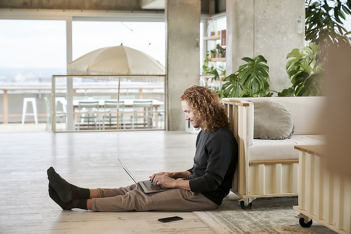 male Mid adult man using laptop sitting on floor at home, Photo by Jo Kirchherr