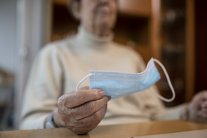 senior Hand of wrinkled woman holding protective face mask during lockdown at home, Photo by Jan Tepass